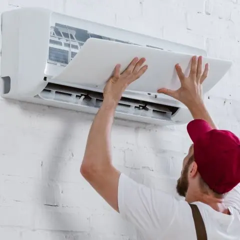 Technician cleaning coils during routine Air Conditioning Service for better performance.
